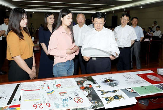6月26日，国务委员、国家禁毒委主任赵克志在北京参加禁毒宣传教育活动。图为赵克志认真观看北京市校园禁毒文化作品展示并与创作这些作品的同学们亲切交谈。